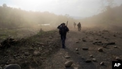 FILE - Counternarcotics officers walk in a clandestine airstrip strewn with boulders, in the Apurimac, Ene and Mantaro River Valleys, or VRAEM, the world's No. 1 coca-growing region, in Junin, Peru, Sept. 19, 2014. 