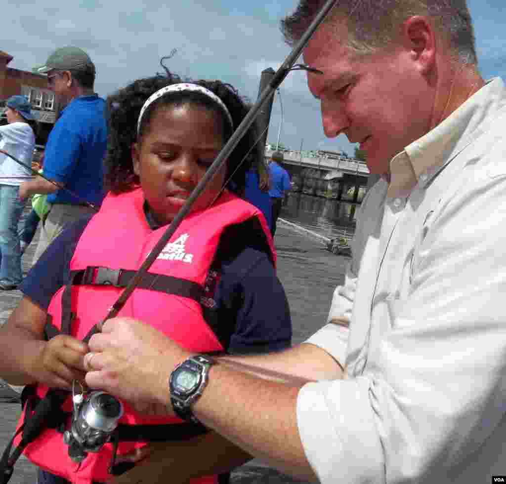 Sukarelawan Layanan Perikanan dan Alam Liar AS Eric mengajari Makayla Gray cara memancing di Sungai Anacostia. (VOA/Rosanne Skirble)