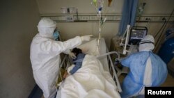Medical workers in protective suits attend to a patient inside an isolated ward of Wuhan Red Cross Hospital in Wuhan, the epicenter of the novel coronavirus outbreak, in Hubei province, China, Feb. 16, 2020.