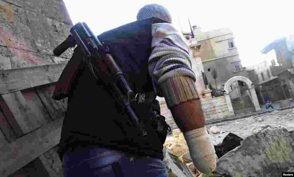 A Free Syrian Army fighter with an amputated hand, takes cover from a sniper loyal to Syria's President Bashar al -Assad, near Aleppo's historic citadel, November 28, 2012.