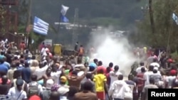 FILE - A still image taken from a video shot on October 1, 2017, shows protesters waving Ambazonian flags as they move forward towards barricades and police amid tear gas in the English-speaking city of Bamenda, Cameroon.