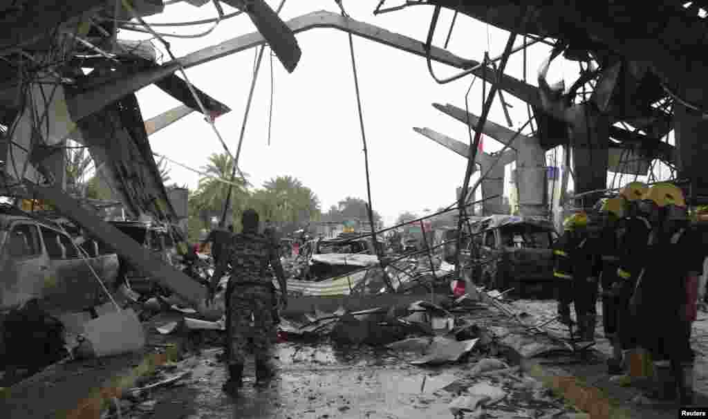 Iraqi security forces and firefighters inspect the site of a suicide attack in Hilla, Iraq, March 9, 2014. 