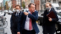 Britain's chief negotiator David Frost, center, removes his face mask to talk to the media as he arrives for Brexit talks with EU chief negotiator Michel Barnier in Brussels, Belgium, Nov. 16, 2020.