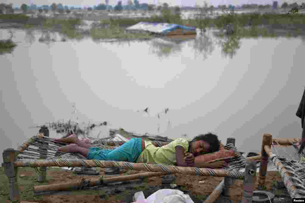Seorang anak pengungsi tidur di luar tenda daruratnya di sebuah kamp di pinggir jalan setelah naiknya air sungai Yamuna akibat hujan lebat di New Delhi. Musim hujan di India diharapkan segera mereda setelah mencapai 89 persen di atas rata-rata pada minggu hingga 19 Juni.