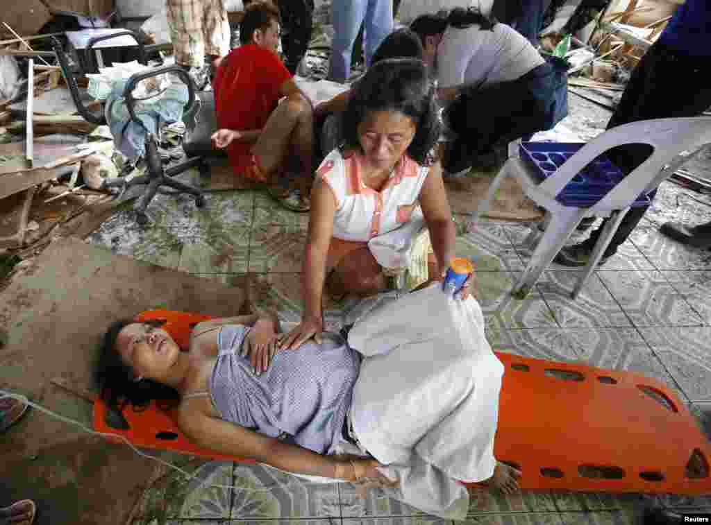Seorang perempuan menenangkan saudaranya yang sedang hamil tua sebelum melahirkan di klinik darurat di kota Tacloban yang dirusak topan Haiyan (11/11). (Reuters/Erik De Castro)
