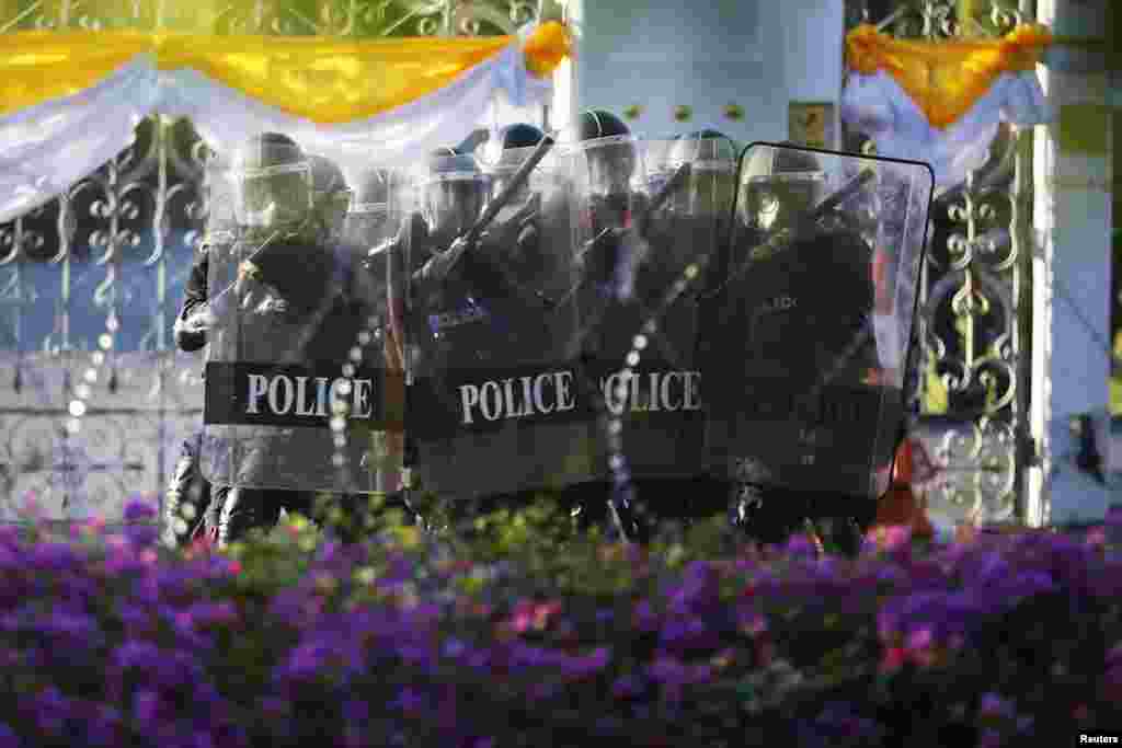 Police move behind their shields as they clash with anti-government protesters near the Government house in Bangkok.