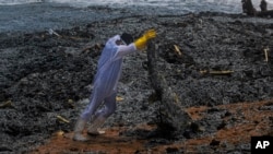 Seorang tentara Angkatan Laut Sri Lanka mengangkut puing-puing yang terdampar di darat dari kapal Singapura yang terbakar MV X-Press Pearl yang berlabuh di lepas pelabuhan Kolombo di Kapungoda, di luar Kolombo, Sri Lanka, Kamis, 27 Mei 2021. (Foto: AP/Eranga Jayawardena )