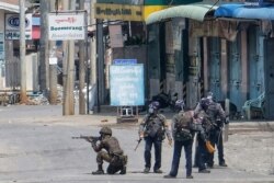 This photo taken and received from an anonymous source via Facebook on March 25, 2021 shows security forces holding weapons on a street in Taunggyi in Myanmar's Shan state. (Handout /Facebook/anonymous/AFP)