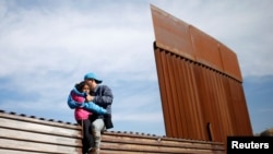 Migrants from Honduras, part of a caravan of thousands from Central America trying to reach the United States, jump onto a border fence to cross illegally from Mexico to the U.S., in Tijuana, Mexico, Dec. 12, 2018. 