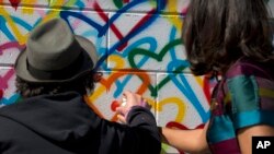 Michelle Obama y el artista Mr. Brainwash pintan un mural en el Día Internacional de la Mujer en Washington D.C., en honor del programa Let Girls Learn, que lidera la Primera Dama. Marzo 8 de 2016.