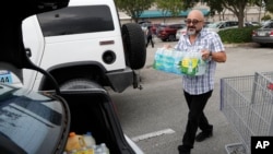 Alvaro Figueroa loads his vehicle with bottled water at BJ's Wholesale Club in preparation for Hurricane Dorian, Aug. 29, 2019, in Hialeah, Fla. Hurricane Dorian is heading towards Florida for a possible direct hit on the state over Labor Day. 