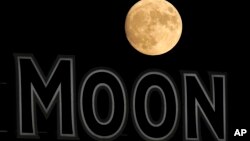 ARCHIVO - La luna se eleva más allá de un letrero en el estadio durante la quinta entrada de un partido de béisbol entre los Kansas City Royals y los Chicago White Sox en agosto de 2022, en Kansas City, EEUU.