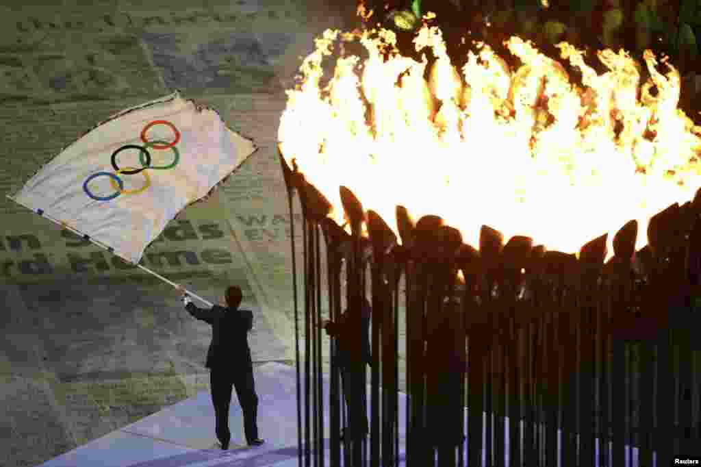 Rio de Janeiro Mayor Eduardo Paes waves the Olympic flag after receiving it from IOC President Jacques Rogge at the closing ceremony of the London 2012 Olympic Games, August 12, 2012.