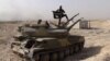 FILE - An Islamic State militant holds the group's flag as he stands on a tank captured from Syrian government forces, in the town of al-Qaryatayn southwest of Palmyra, central Syria. 
