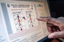 A staff member gestures towards a screen displaying how a ballot paper should be marked during the upcoming elections at the electoral commission headquarters in Kampala, Uganda, Jan. 2, 2021.