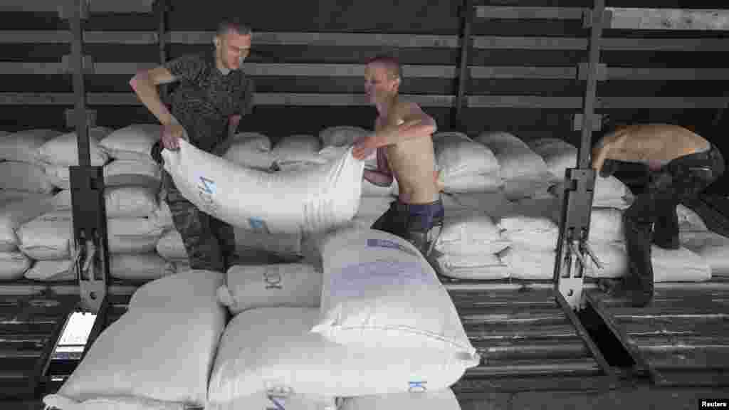 People lift up sacks which are part of a Russian convoy carrying humanitarian aid in Donetsk, eastern Ukraine, Sept. 20, 2014.
