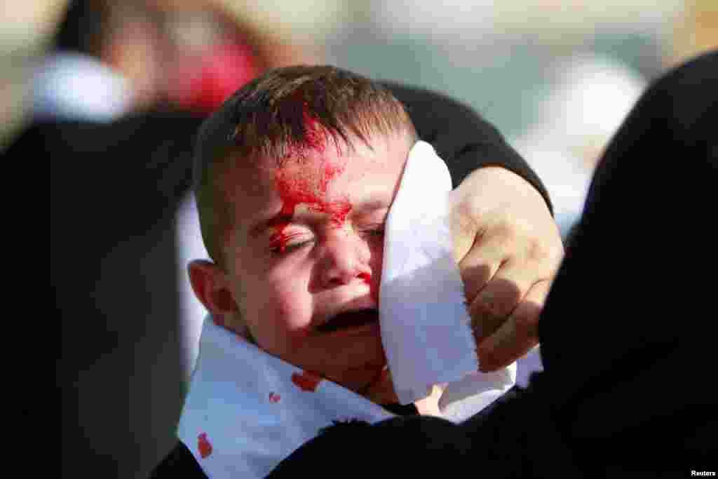 A Shi'ite Muslim child reacts as he bleeds after he was cut on the forehead with a razor during a religious procession to mark Ashura in Nabatiyeh town, southern Lebanon, October 12, 2016.