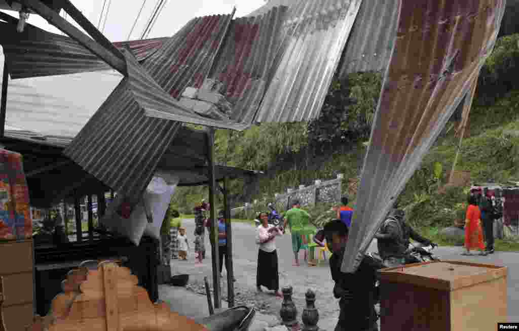 Residents stay outside their damaged house after it was hit by a strong earthquake in Bener Meriah district, July 2, 2013.