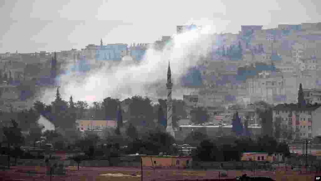 Smoke rises following a strike in Kobani, Syria, during fighting between Syrian Kurds and the militants of Islamic State group, as seen from a hilltop on the outskirts of Suruc, at the Turkey-Syria border, Oct. 19, 2014.