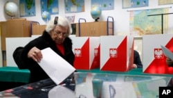 A voter casts her ballot at a polling station in Warsaw, Poland, Oct. 13, 2019. Voters in Poland and Hungary vote Sunday in parliamentary elections.