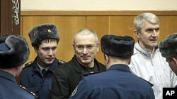 Mikhail Khodorkovsky, center, and his co-defendant Platon Lebedev, right, are escorted to a court room in Moscow, 27 Dec 2010.