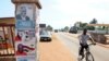 A man rides past a pillar featuring posters of the ruling party presidential candidate, incumbent President John Mahama, and opposition candidate Nana Akufo-Addo in Accra, Oct. 23, 2012.