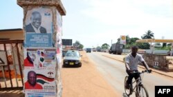 A man rides past a pillar featuring posters of the ruling party presidential candidate, incumbent President John Mahama, and opposition candidate Nana Akufo-Addo in Accra, Oct. 23, 2012.