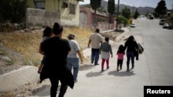ARCHIVO - Una migrante hondureña junto a su hija caminan después de haber sido deportadas de Estados Unidos hacia Ciudad Juárez, en México. 22 de junio de 2020.