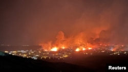 Gedung-gedung terbakar saat kobaran api yang disebabkan oleh angin kencang melalap rumah warga, dan memaksa ribuan warga dievakuasi di Denver, Colorado, pada 30 Desember 2021. (Foto: Gregg Corella/Handout via Reuters) 