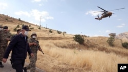 FILE - Turkish Defense Minister Hulusi Akar, left, visits Turkish troops at the border with Iraq, in Hakkari province, June 19, 2020.