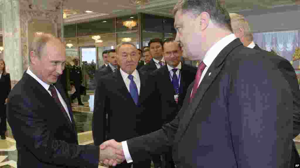 Russian President Vladimir Putin, left, shakes hands with Ukrainian President Petro Poroshenko as Kazakh President Nursultan Nazarbayev looks on prior to their talks in Minsk, Belarus, Aug. 26, 2014.