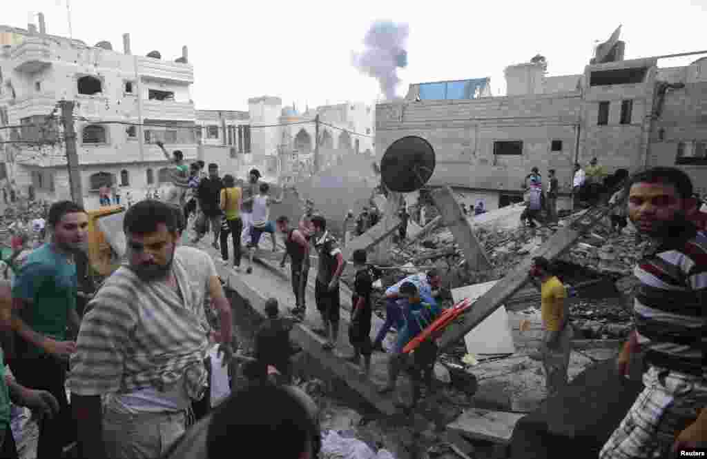 Smoke rises from buildings following what witnesses said was an Israeli air strike, as Palestinians search for victims under the rubble of a house that police said was destroyed in another Israeli air strike in Rafah in the southern Gaza Strip, July 11, 2