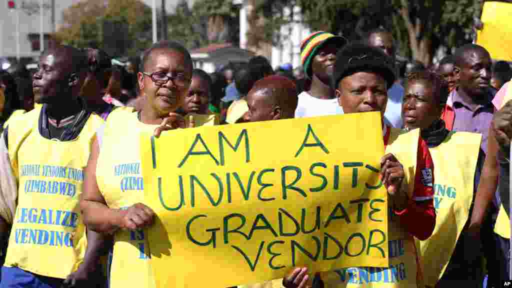 Une vendeuse de rue du Zimbabwe écrit sur une banderole qu’elle est diplômée d’université, exhortant le gouvernement à arrêter de les chasser lors d'une manifestation à Harare, le 24 juin 24, 2015.