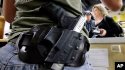 FILE - Kayla Brown, left, wears her gun on her hip while working at the Spring Guns and Ammo store in Spring, Texas, JAN. 4, 2016.