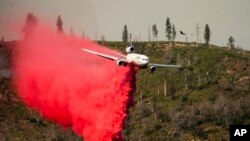 Pesawat pemadam kebakaran menyemprotkan retardant untuk menghentikan kebakaran lahan meluas di wilayah Mariposa, California, pada 24 Juli 2022. (Foto: AP/Noah Berger)