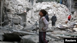 FILE - A boy inspects a damaged site after airstrikes on the rebel held Tariq al-Bab neighbourhood of Aleppo, Syria, Sept. 23, 2016. 