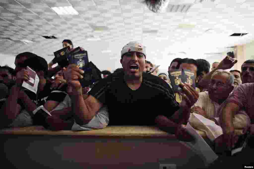 Seorang pria mencoba menyeberang ke Mesir berteriak sambil memegang paspor miliknya dan keluarganya ketika menunggu di penyeberangan Rafah antara Mesir dan selatan Jalur Gaza, 16 Juli 2014.
