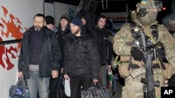 Seorang prajurit Ukraina berjalan di dekat para separatis pro-Rusia dalam pertukaran tawanan perang di dekat Donetsk Ukraina timur, 26/12/2014.