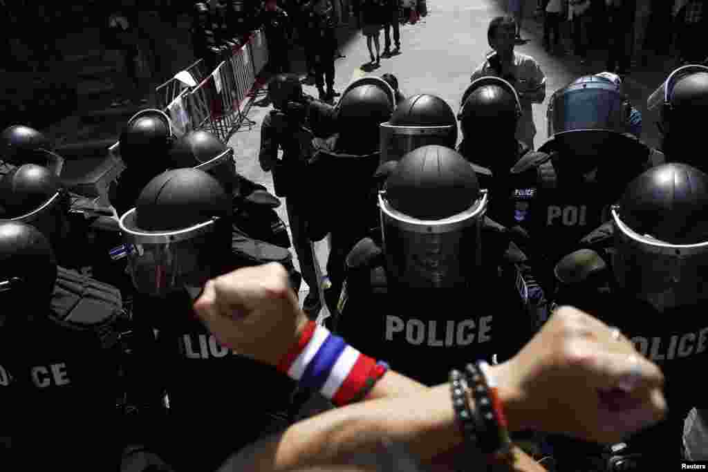 An anti-government protester gestures towards riot police outside the headquarters of the ruling Puea Thai Party of Prime Minister Yingluck Shinawatra in Bangkok, Nov. 29, 2013.