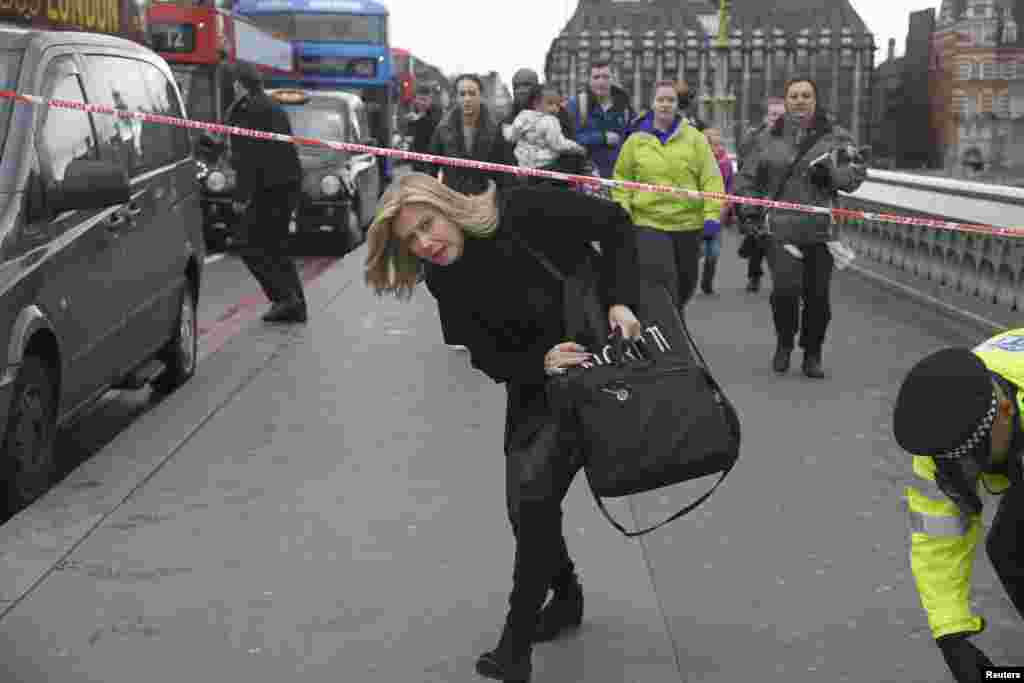 A woman ducks under a police tape after an incident on Westminster Bridge in London, March 22, 2017.