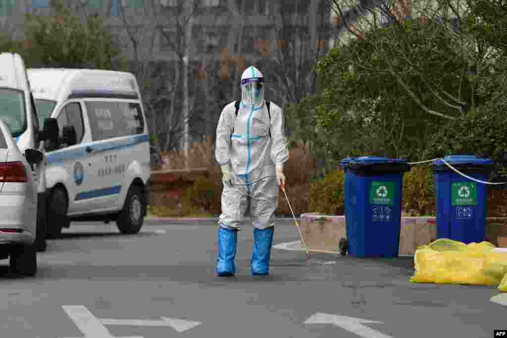 A staff member sprays disinfectant outside a hotel after one person tested positive for the COVID-19 coronavirus, in Nanjing in China's eastern Jiangsu province.