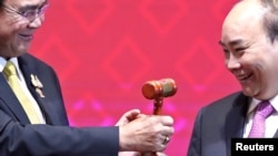 Vietnam's Prime Minister Nguyen Xuan Phuc takes the gavel from Thai Prime Minister Prayuth Chan-Ocha who hands over the ASEAN chairmanship to Vietnam during the closing ceremony of the 35th ASEAN Summit and related summits in Bangkok, Thailand,…