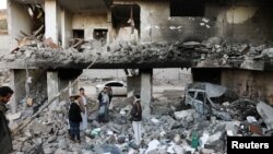 Des gardes se tiennent sur les décombres d'une maison touchée par des frappes aériennes menées par l'Arabie saoudite à Sanaa, au Yémen, le 18 janvier 2022.