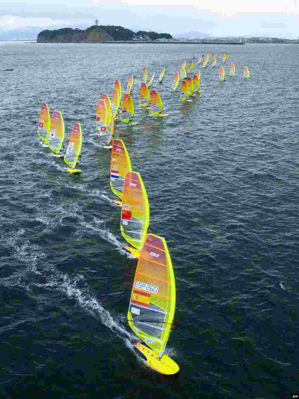 An aerial view shows competitors taking part in the men's RS:X class windsurfing event as part of the sailing World Cup series, a test event ahead of the upcoming Tokyo 2020 Olympic Games, in the waters off Enoshima island.