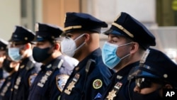 FILE - New York Police Department officers in masks stand during a service at St. Patrick's Cathedral in New York to honor 46 colleagues who have died of COVID-19-related illnesses, Oct. 5, 2020.