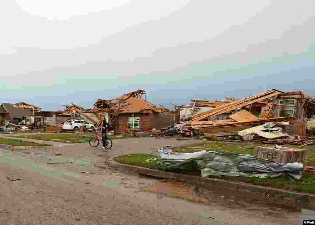 Seorang gadis dengan sepedanya mengamati aksi tanggap darurat setelah tornado melanda kota Moore, Oklahoma.