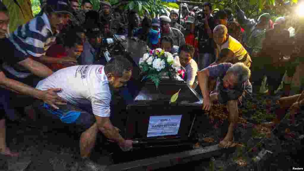 Relatives lower the coffin containing the body of Hayati Lutfiah, a passenger of AirAsia Flight 8501, during her burial at a cemetery in Surabaya, Jan. 1, 2015.
