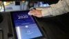 A poll worker sanitizes a voting screen at a polling station on Super Tuesday, March 3, 2020 in Los Angeles, California