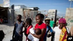 Milene Monime, 16, holding her two month old son Jefferson Thezan, stands along with other Haitian migrants just deported from Dominican Republic, at the border crossing in Malpasse, Haiti, June 17, 2015. 