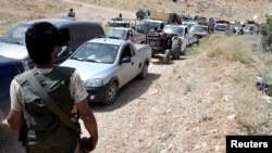 Hezbollah members escort a convoy of Syrian refugees at the border town of Arsal, Lebanon, July 12, 2017. Hezbollah and the Syrian army Friday launched an offensive against insurgents along the border.